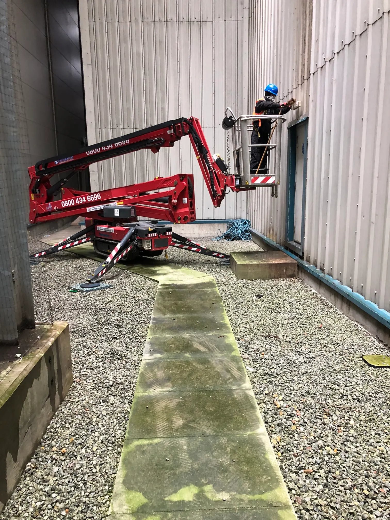 DGH operative working from a tracked spider lift in a narrow gap between buildings