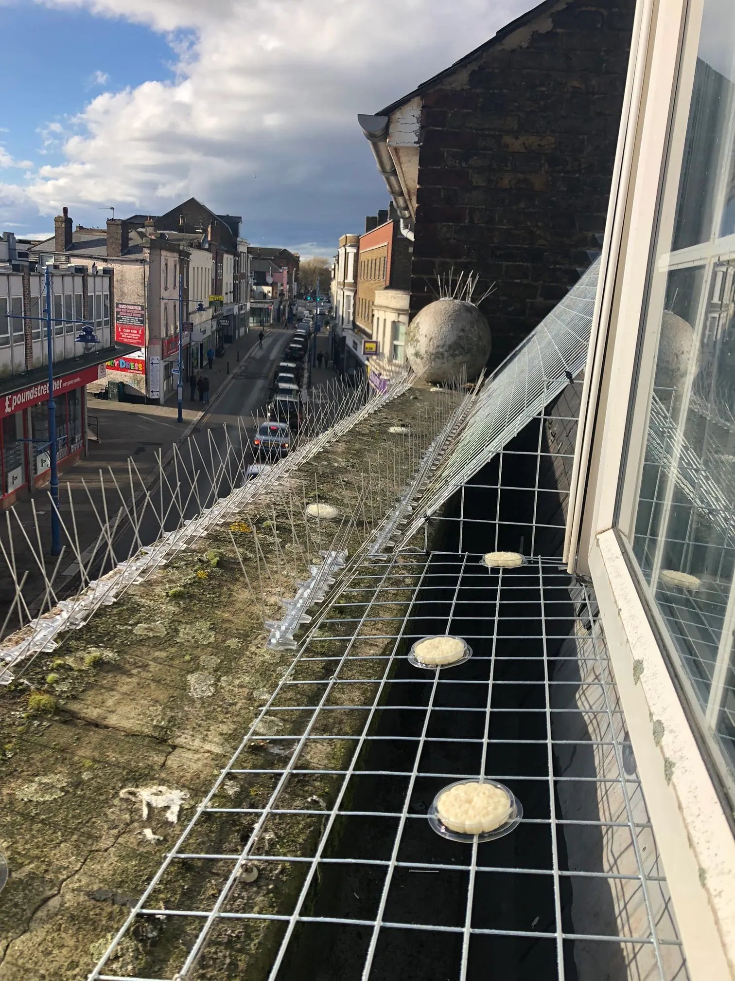 Bird netting running the length of a building ledge above the town